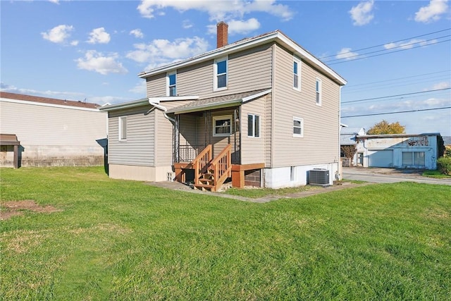 rear view of house featuring central AC and a yard