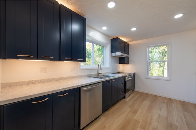 kitchen with appliances with stainless steel finishes, light stone countertops, sink, and light hardwood / wood-style floors