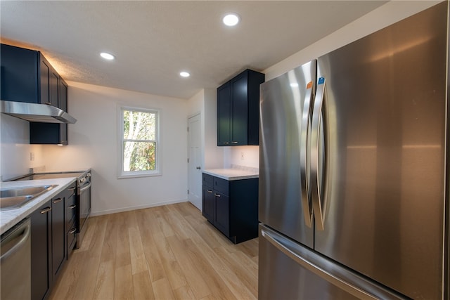 kitchen featuring appliances with stainless steel finishes, blue cabinetry, sink, and light hardwood / wood-style floors