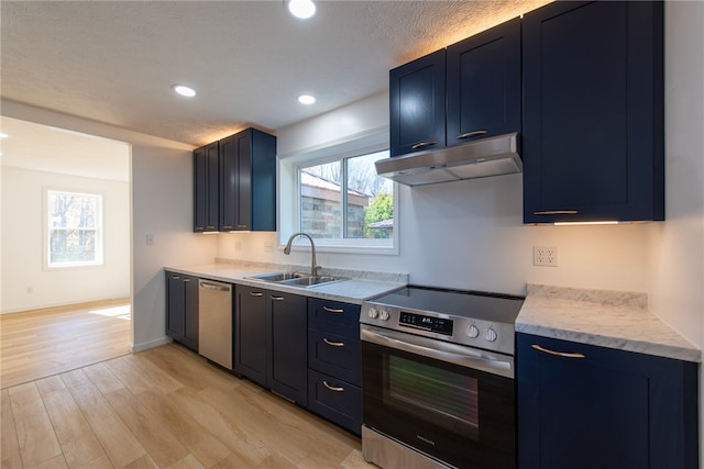 kitchen featuring sink, light wood-type flooring, a textured ceiling, blue cabinets, and stainless steel appliances