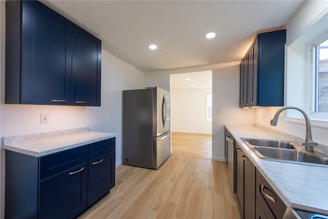 kitchen with blue cabinets, sink, stainless steel appliances, and light hardwood / wood-style floors