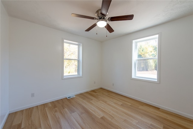 spare room with a wealth of natural light, light hardwood / wood-style flooring, and ceiling fan