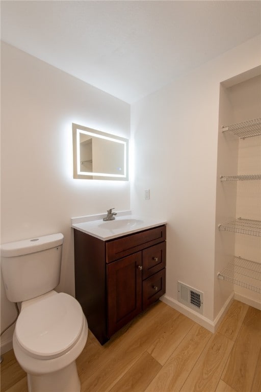 bathroom with vanity, toilet, and hardwood / wood-style flooring