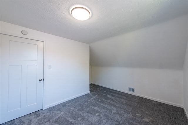 bonus room with lofted ceiling, a textured ceiling, and dark carpet