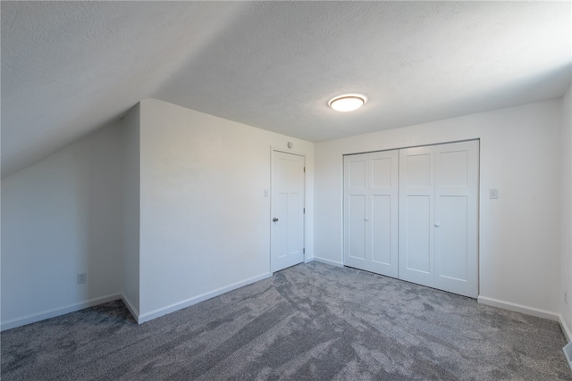 interior space featuring lofted ceiling, dark colored carpet, and a textured ceiling