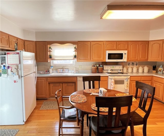 kitchen featuring decorative backsplash, white appliances, light hardwood / wood-style floors, and sink