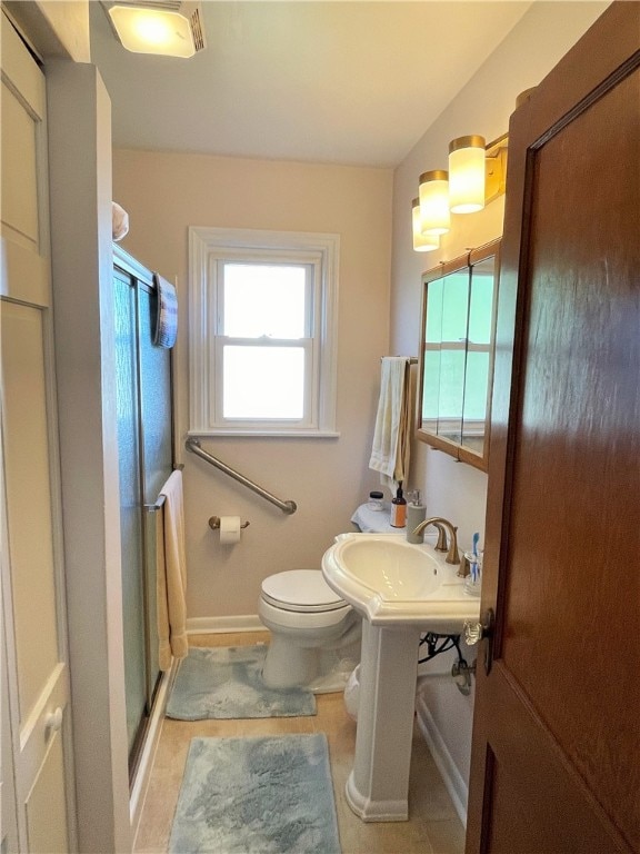 bathroom featuring toilet, tile patterned floors, and a shower with door