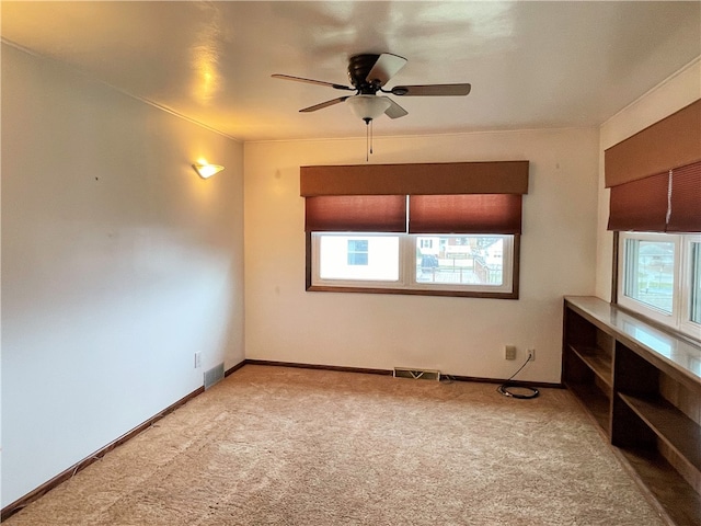 empty room with light carpet, plenty of natural light, and ceiling fan