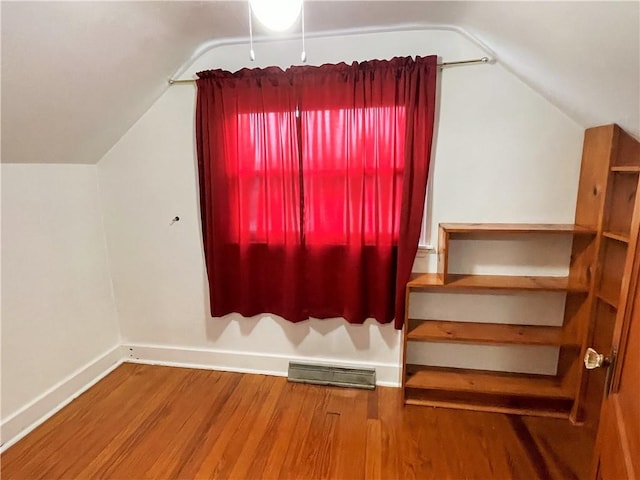 additional living space with hardwood / wood-style floors and vaulted ceiling