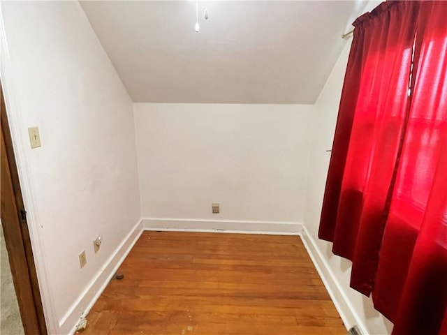 additional living space with wood-type flooring and vaulted ceiling