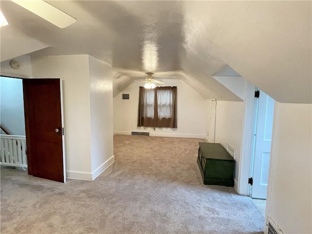 additional living space with ceiling fan, a baseboard radiator, light carpet, and vaulted ceiling