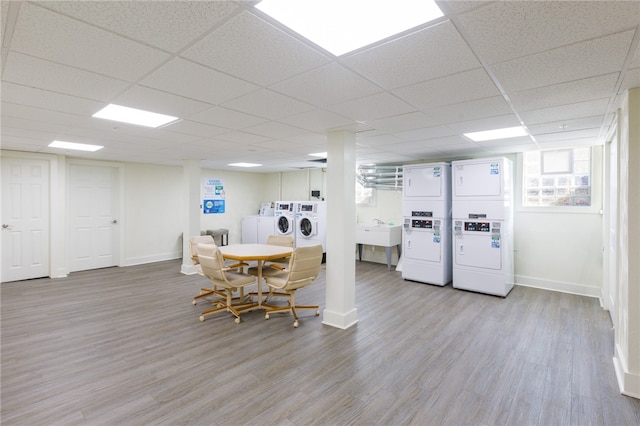 dining area with stacked washer / drying machine, sink, a drop ceiling, light wood-type flooring, and washing machine and clothes dryer