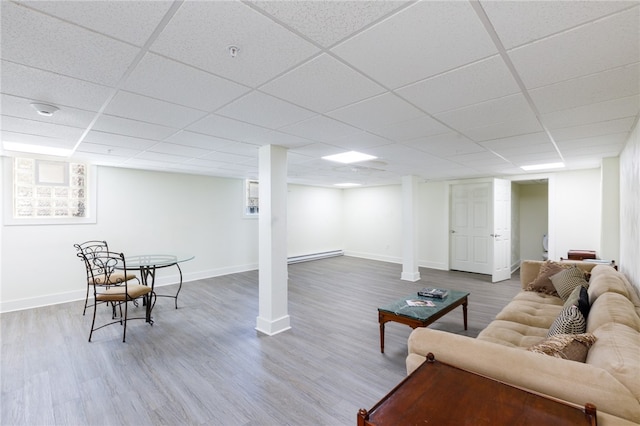 living room featuring wood-type flooring, a drop ceiling, and baseboard heating