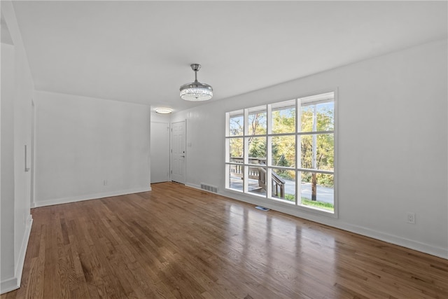 unfurnished living room with hardwood / wood-style floors and an inviting chandelier