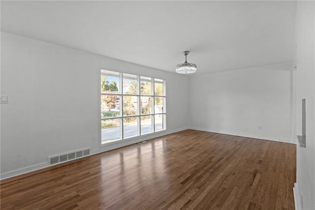 unfurnished room featuring dark hardwood / wood-style flooring and an inviting chandelier