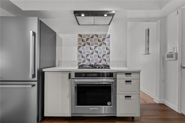 kitchen with white cabinets, stainless steel appliances, tasteful backsplash, and dark hardwood / wood-style flooring