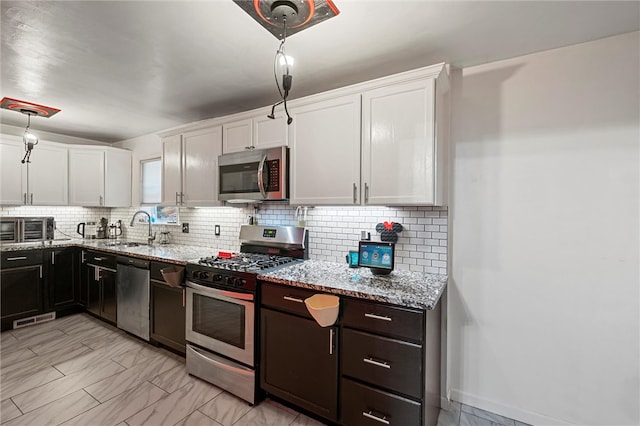 kitchen with white cabinetry, backsplash, appliances with stainless steel finishes, and hanging light fixtures