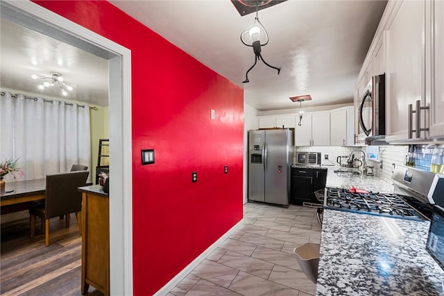 kitchen featuring white cabinets, backsplash, light stone countertops, sink, and stainless steel appliances