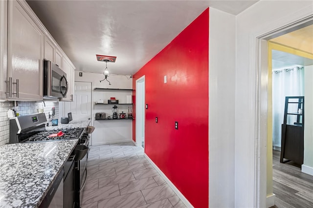 kitchen with appliances with stainless steel finishes, decorative light fixtures, white cabinets, light stone counters, and decorative backsplash