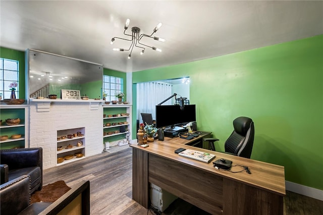 office space featuring an inviting chandelier, wood-type flooring, and a brick fireplace