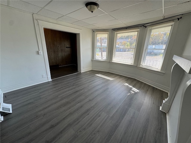 unfurnished dining area with dark wood-type flooring and a paneled ceiling