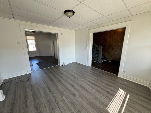 unfurnished room featuring dark wood-type flooring and a drop ceiling