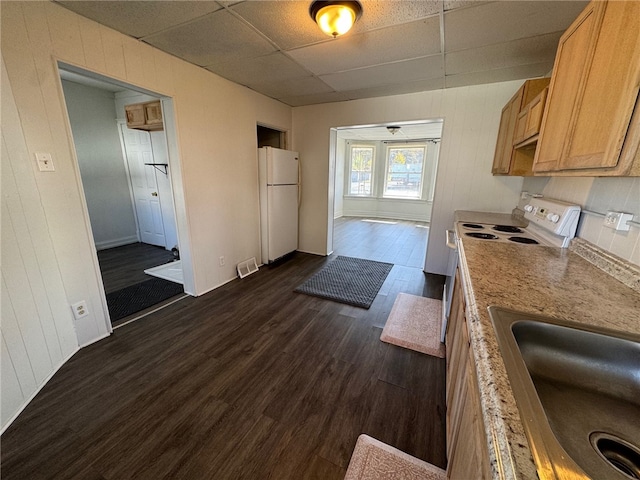 kitchen with wood walls, sink, a drop ceiling, dark hardwood / wood-style flooring, and white refrigerator