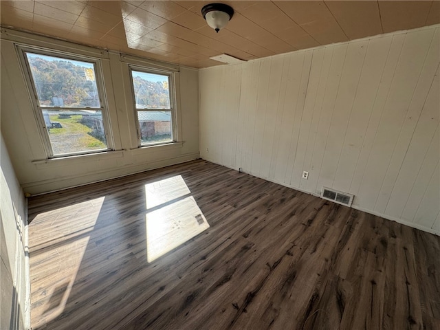 spare room featuring dark wood-type flooring and wood walls