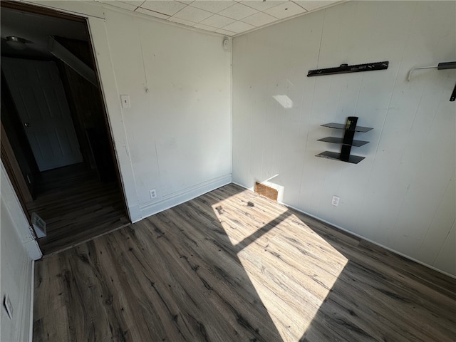 spare room featuring wooden walls and dark hardwood / wood-style flooring