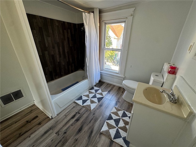 full bathroom featuring toilet, hardwood / wood-style flooring, vanity, and shower / tub combo