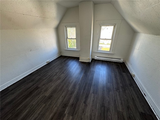 additional living space with a baseboard radiator, a textured ceiling, lofted ceiling, and dark hardwood / wood-style flooring