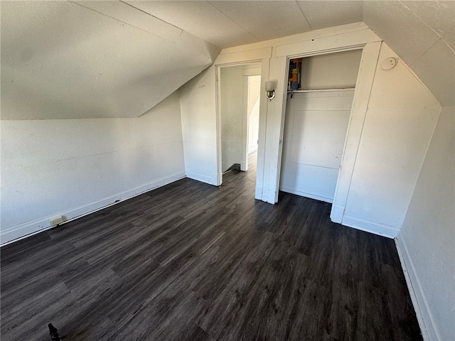 unfurnished bedroom featuring lofted ceiling, a closet, and dark wood-type flooring