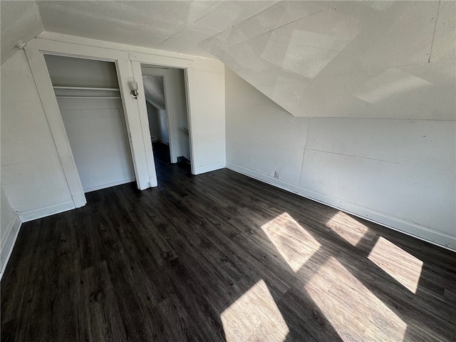 unfurnished bedroom featuring dark wood-type flooring and vaulted ceiling