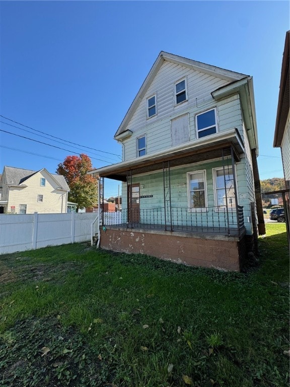 rear view of property featuring covered porch and a lawn