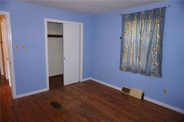 unfurnished bedroom featuring a closet and dark hardwood / wood-style flooring