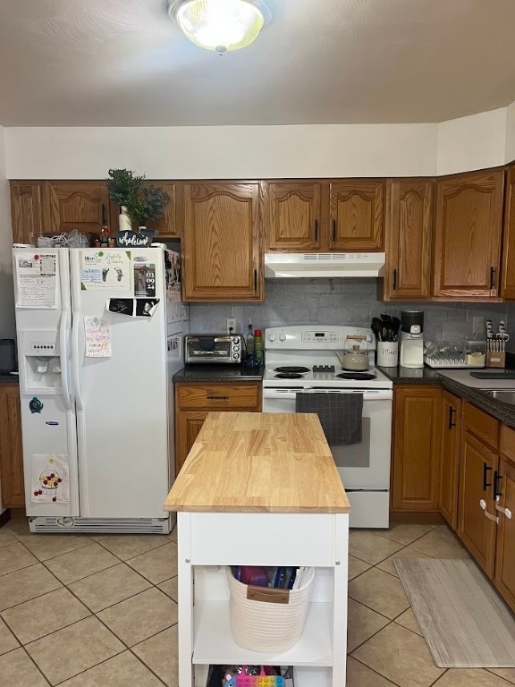 kitchen with decorative backsplash, butcher block counters, white appliances, and light tile patterned floors