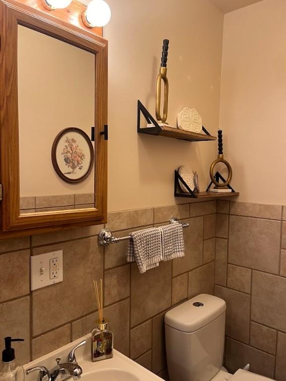 bathroom featuring sink, tile walls, and toilet