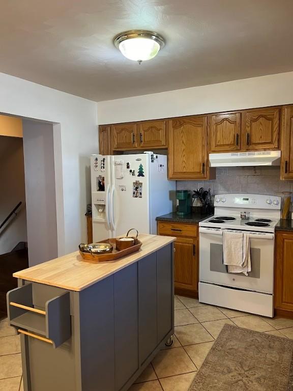 kitchen with light tile patterned floors, wooden counters, white appliances, and decorative backsplash