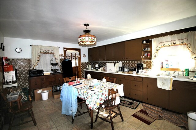 kitchen with sink, dark brown cabinetry, pendant lighting, light tile patterned floors, and tasteful backsplash