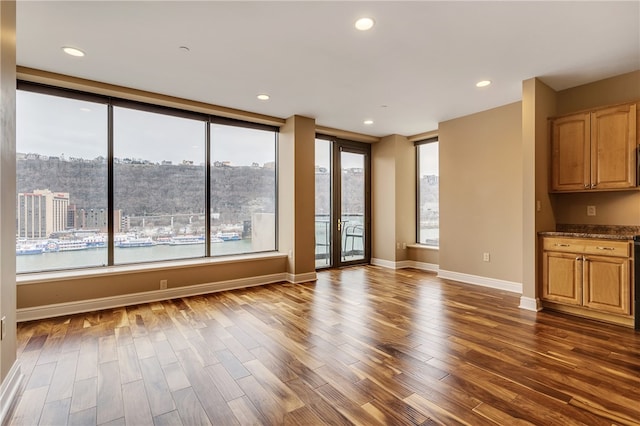 unfurnished living room featuring a water view and dark hardwood / wood-style flooring