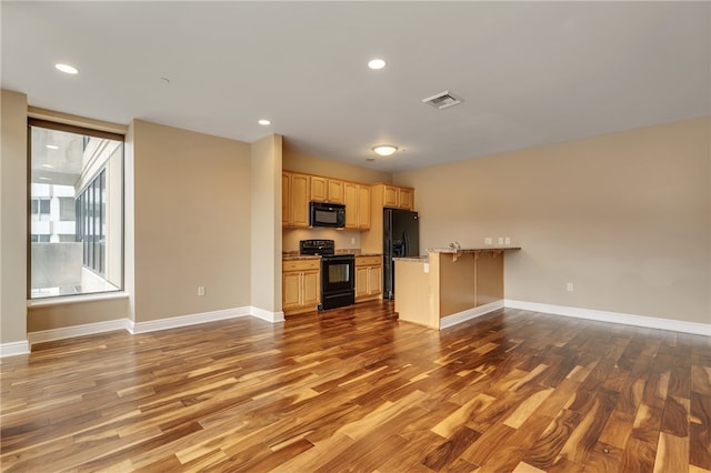 kitchen featuring black appliances, light brown cabinets, dark wood-type flooring, and kitchen peninsula