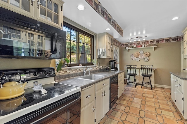 kitchen with cream cabinets, black appliances, sink, and light tile patterned floors