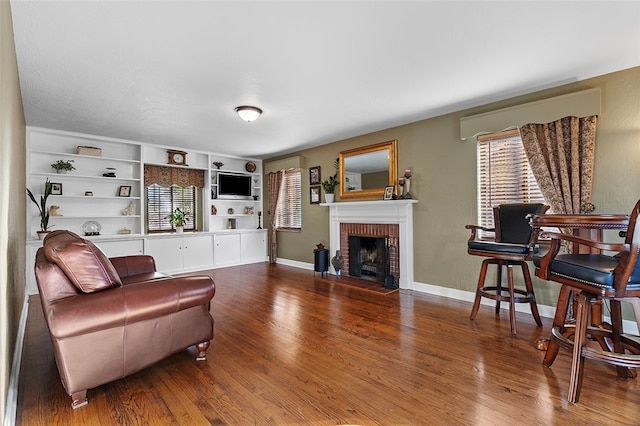 living room with hardwood / wood-style floors, a brick fireplace, and built in features