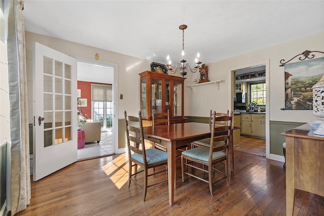 dining area with sink, a chandelier, and wood-type flooring