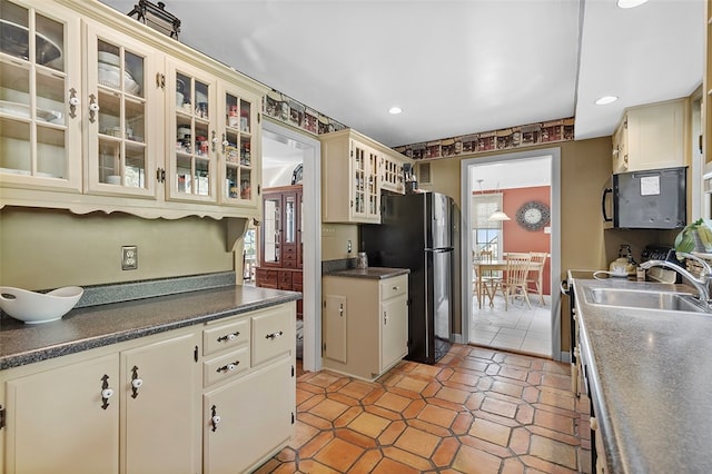 kitchen with stainless steel fridge, sink, light tile patterned floors, and cream cabinetry