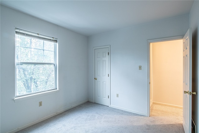 unfurnished bedroom featuring light carpet and multiple windows