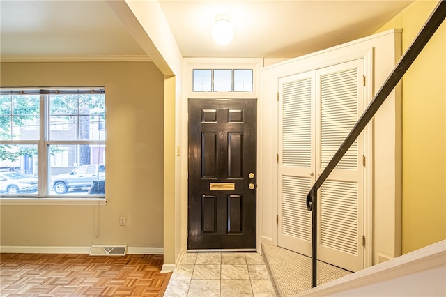 foyer entrance with crown molding and light parquet flooring