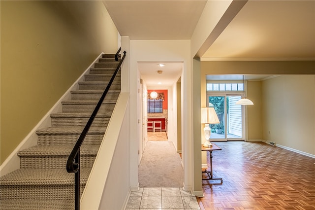 stairway featuring ornamental molding and parquet floors