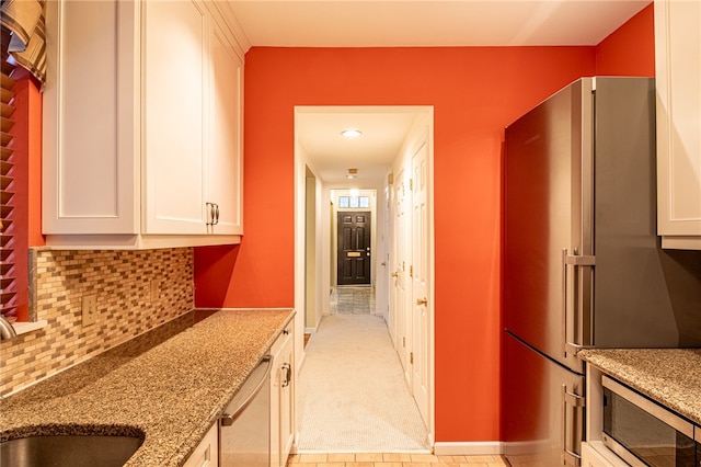 kitchen featuring light stone countertops, sink, backsplash, stainless steel appliances, and white cabinets