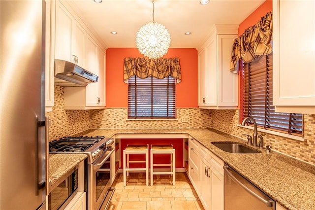 120 S 13th St, South Side, PA 15203 - kitchen with stainless steel appliances, under cabinet range hood, a sink, white cabinetry, and a notable chandelier